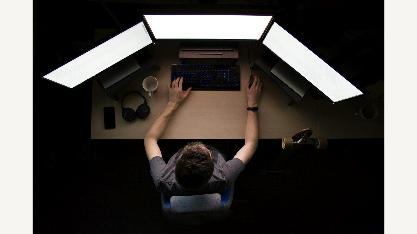 A person working at multiple monitors in a dark room