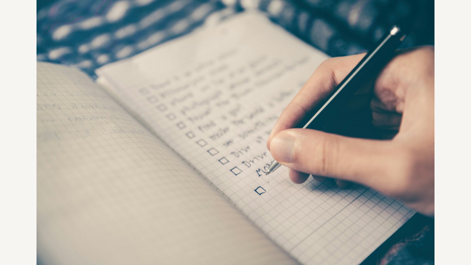 A person taking notes beside a laptop