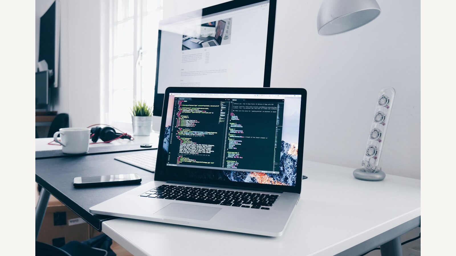 A laptop showing code on a white desk