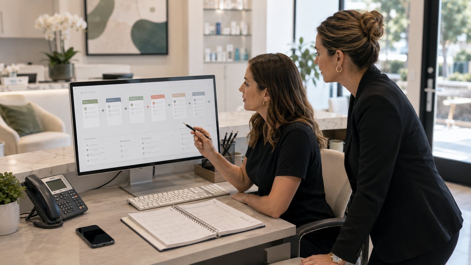 Med spa coordinator reviewing a client follow-up workflow on a desktop screen while managing appointment messages at a reception desk